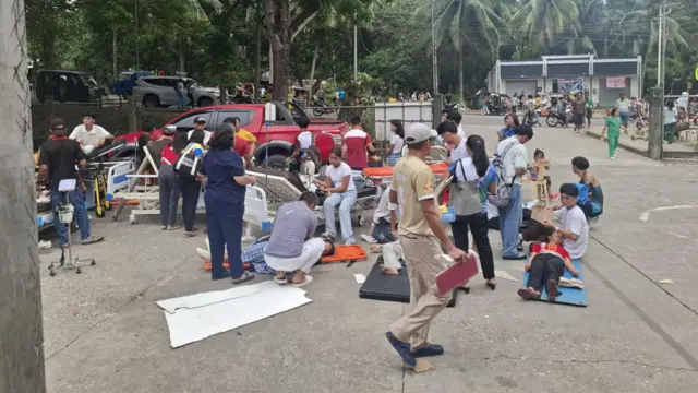 people gather on an open court, some are receiving medical treatment