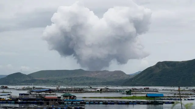 Ash rises from a volcano near a fish farm during an eruption in the Philippines