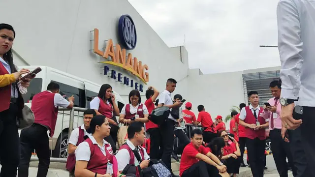 Employees at a shopping mall gather outside the building in Davao City