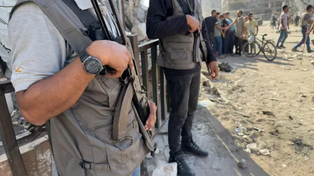 A close up shot of the guns held by two men. Others can been seen in the background of the shot