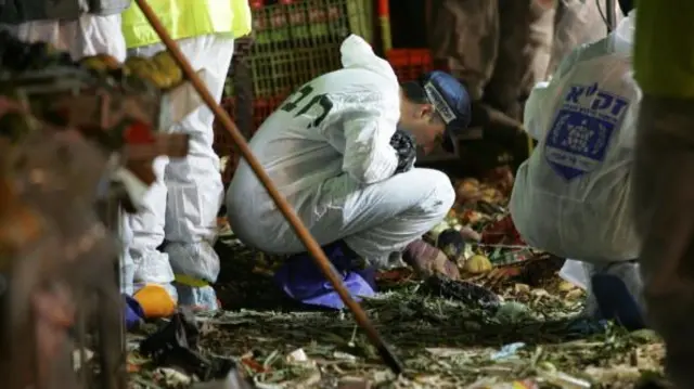 Forensics experts in white suits sift through rubble
