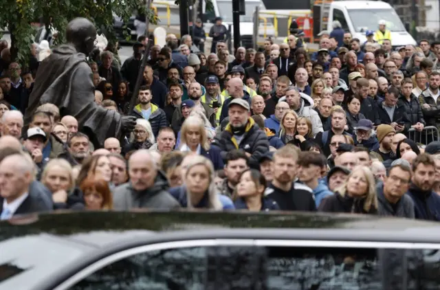 Mourners look on as the funeral cortege of Ricky Hatton passes by