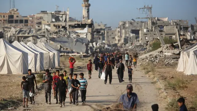 Palestinians walk along a dusty road
