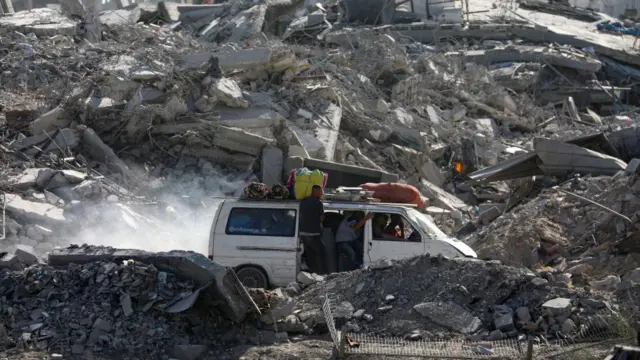 Rubble in Gaza, as people travel in a car.