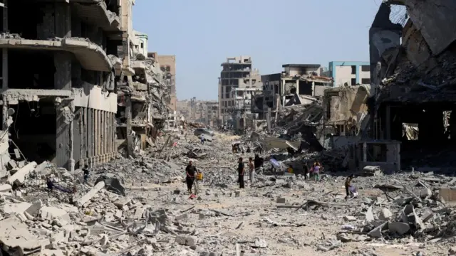 Palestinians walk among rubble following Israeli forces' withdrawal from the area