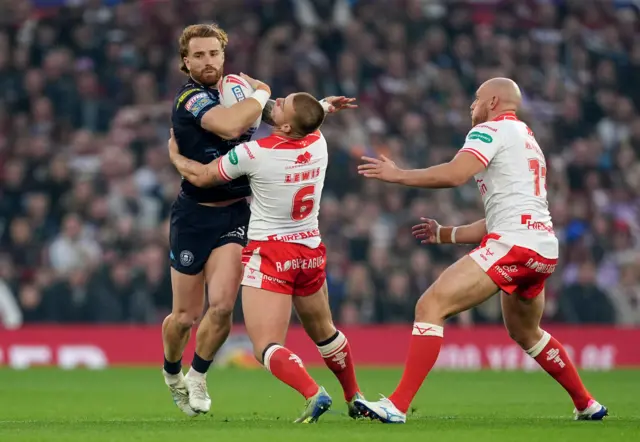 Wigan Warriors' Adam Keighran (left) is tackled by Hull KR's Mikey Lewis (centre)