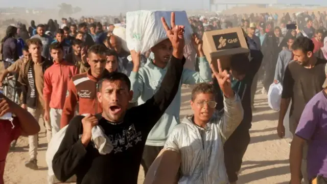 Gazans are seen carrying GHF boxes