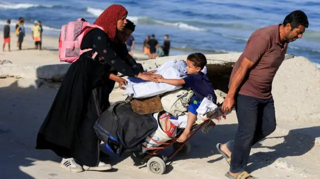 Palestinians, who were displaced to the southern part of Gaza at Israel's order during the war, make their way along a road as they return to the north, amid a ceasefire between Israel and Hamas