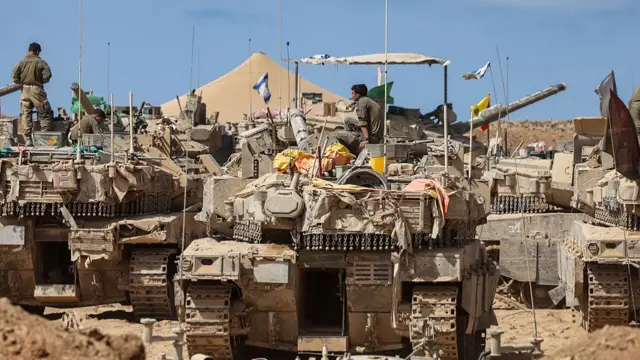 Israeli soldiers carry out maintenance on tanks positioned in southern Israel, on the border with the Gaza Strip