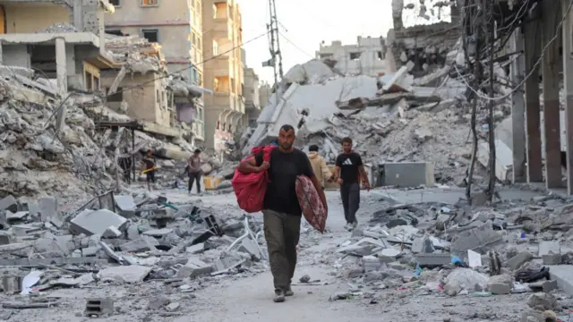 Palestinians walk near rubble in the aftermath of an Israeli offensive carried out before a ceasefire between Israel and Hamas was reached, at Shati`refugee camp in Gaza City