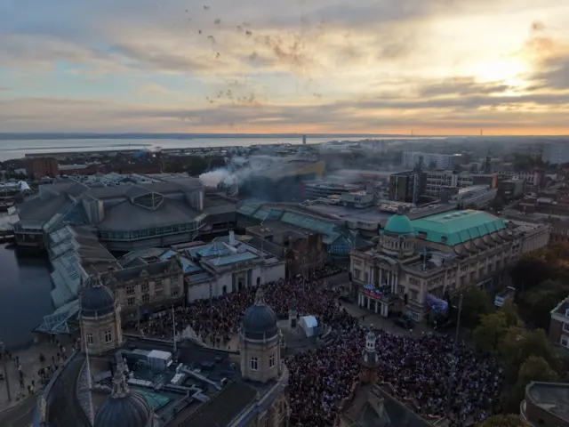 An aerial view of Queen Victoria Square. Thousands of people are packed into a square with smoke in the air from a firework display