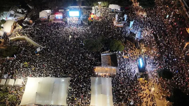 An overhead view of Hostages Square. Several screens and tents around the edges.