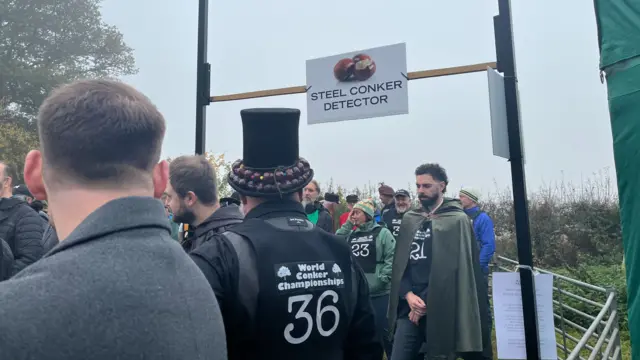 People were lining up to go through a conker security gate which has a sign over the entrance.