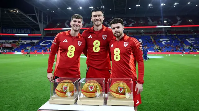 Chris Mepham, Kieffer Moore and Neco Williams of Wales pose for a photo with their 50th caps
