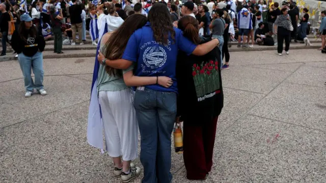 Women hold one another as people gather at "Hostages Square"