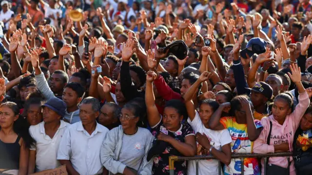 Protesters gesture, as family members of Safidy Rakooarisoa who they say died during demonstrations, bring his body to a gathering outside the town hall on Independence Avenue for prayers, as protesters gesture during a nationwide youth-led protest against frequent power outages and water shortages, in Antananarivo, Madagascar, October 13, 2025