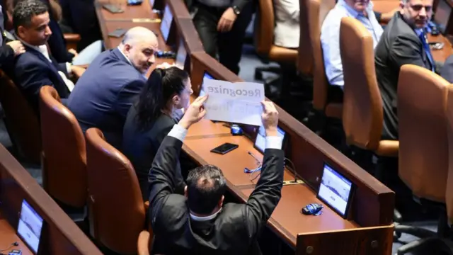 An Israeli member of parliament holds a placard that reads: 'Recognize Palestine!'