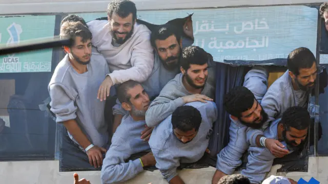 Men in grey sweatshirts lean out of a bus