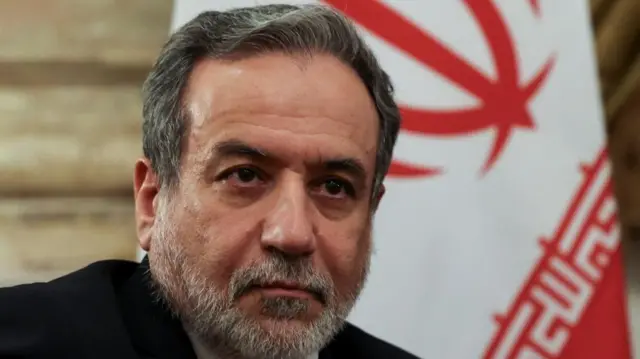 Iran's Foreign Minster Abbas Araghchi, looking off camera to the right, with a partial Iranian flag in background