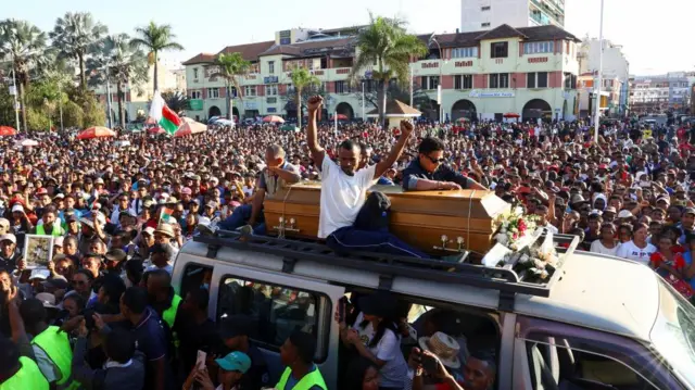 Family members of Safidy Rakooarisoa, who they say died during demonstrations, bring his body to a gathering outside the town hall on Independence Avenue for prayers, as protesters gesture during a nationwide youth-led protest against frequent power outages and water shortages, in Antananarivo, Madagascar, October 13, 2025