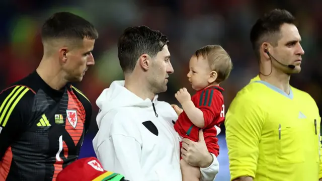 Ben Davies holds small child in arms