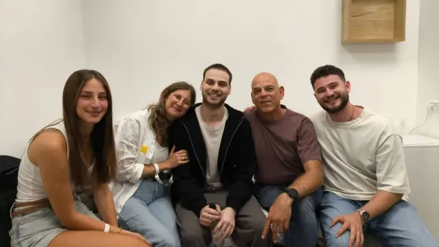 Five people sat down and smiling at camera