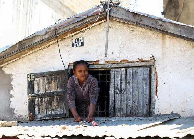 A resident watches protesters march during a nationwide youth-led protest over frequent power outages and water shortages, in Antananarivo, Madagascar, October 13, 2025. REUTERS/Siphiwe Sibeko