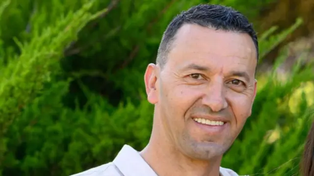 A man in a white shirt in front of some green grass