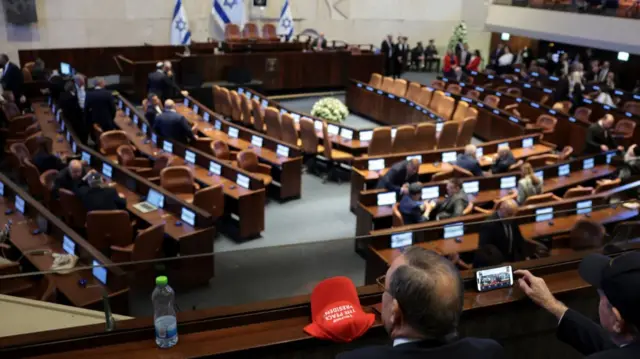 Wide shot of the Knesset from the audience section two men sit down and take pictures
