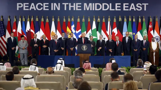 A group of leaders stand in front of flags and a sign reading 'Peace in the Middle East'