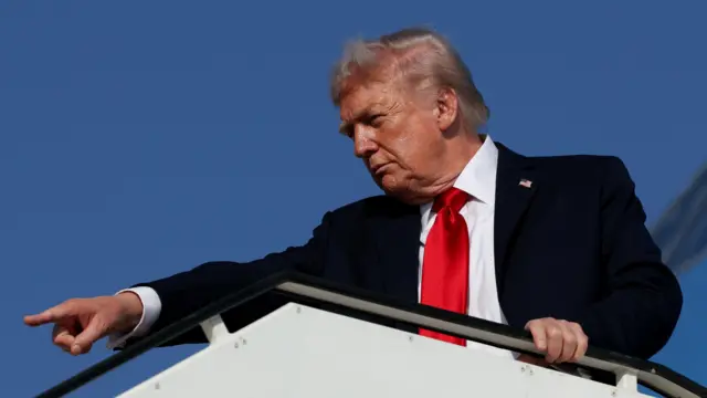 Trump gestures as he boards Air Force One