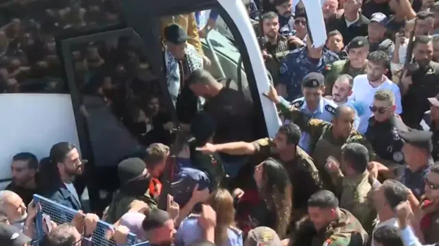 Palestinian prisoners walk of bus surrounded by crowds