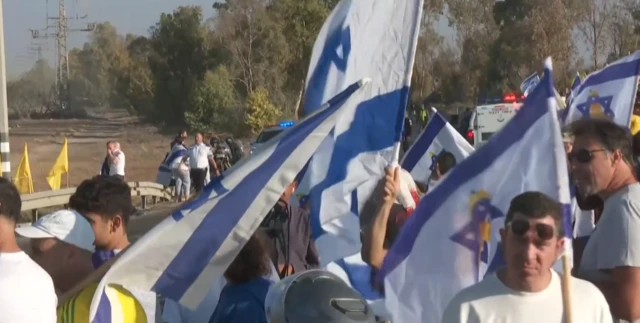 People are gathered with Israeli flags at the Re'im military base in southern Israel