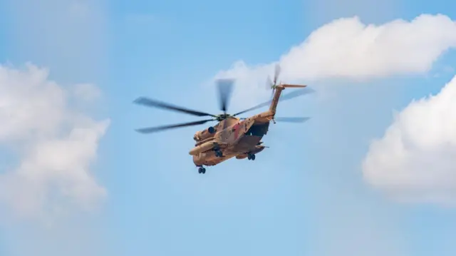 Helicopter flying in a partly cloudy sky