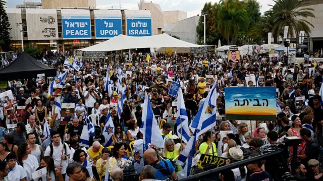 A crowd gathering in an open space, many waving Israeli flags