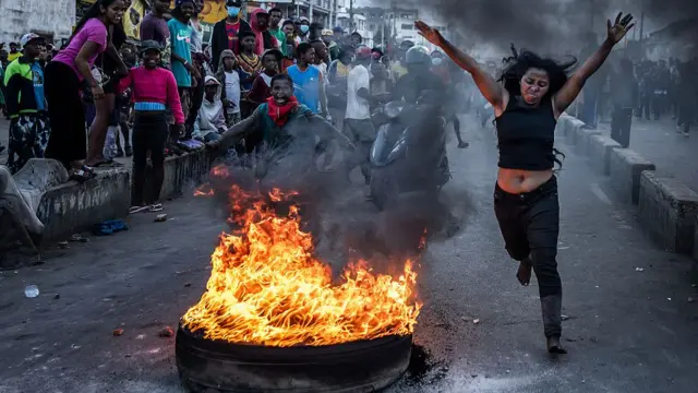 A protester runs past a burning tyre