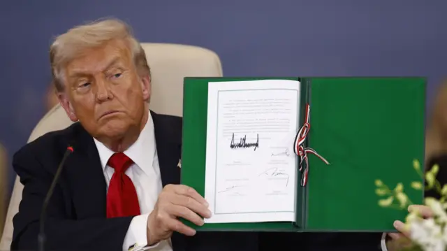 US President Donald Trump shows a signed document at the Gaza Peace Summit in Sharm El-Sheikh, Egypt