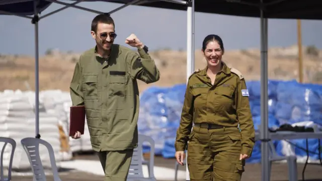 A man in green clothes stands next to a female IDF soldier