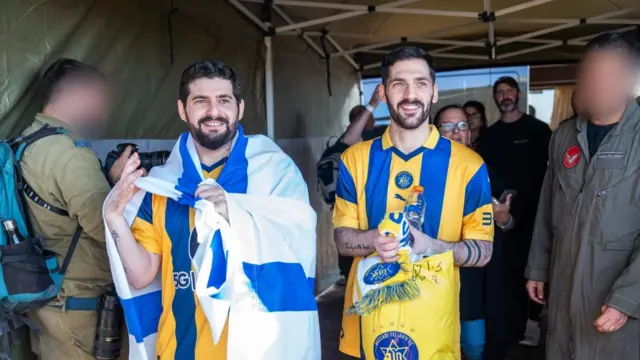 Two men smiling in footbal shirts