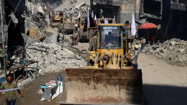 A line of diggers drive through a road in Gaza City