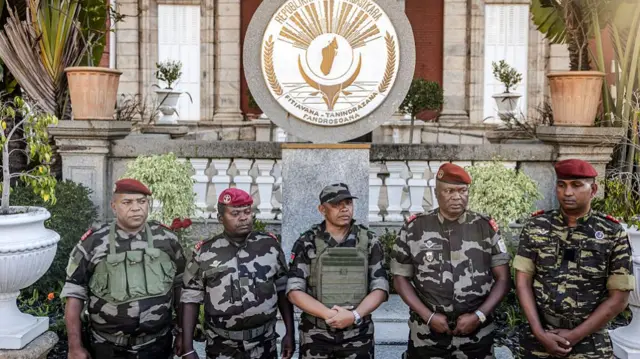 Men in military uniforms stand in a line in front of the palace
