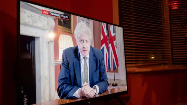 An image taken from inside a living room shows a TV screen on which former Prime Minister Boris Johnson is addressing the nation live from Downing Street during the Covid pandemic.