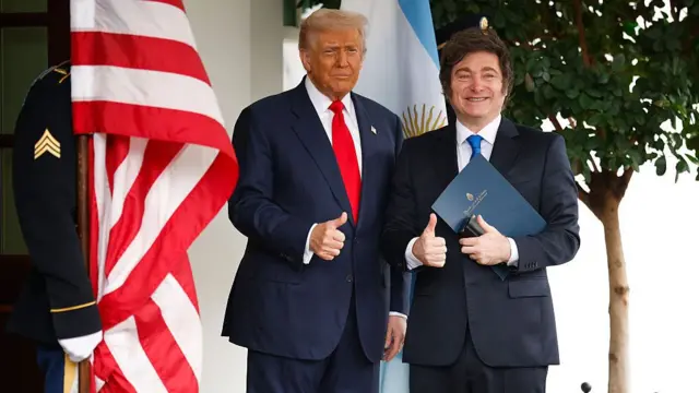 Trump stands with Milei. Both are in dark suits and giving a thumbs up to cameras