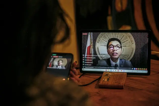 A resident of Antananarivo watches Madagascar President Andry Rajoelina's address to the nation via the official Facebook page of the Presidency of Madagascar, from her home in Antananarivo on October 13, 2025. Madagascar's embattled President Andry Rajoelina said on October 13, 2025 he was sheltering in a "safe space" after an attempt on his life. "I was forced to find a safe place to protect my life today. In all this, I never stop looking for solutions," the 51-year-old leader said in a live address on Facebook, without revealing his location.