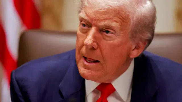 Trump listens to a reporter's question