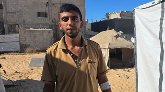 Man in brown t shirt with white plaster wrapped around his left elbow