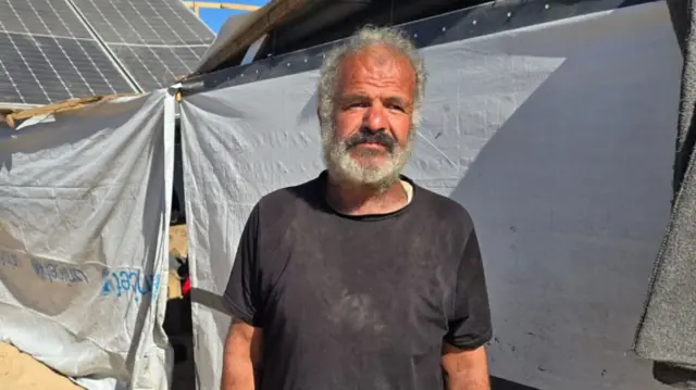 Man with grey hair and beard in black t shirt