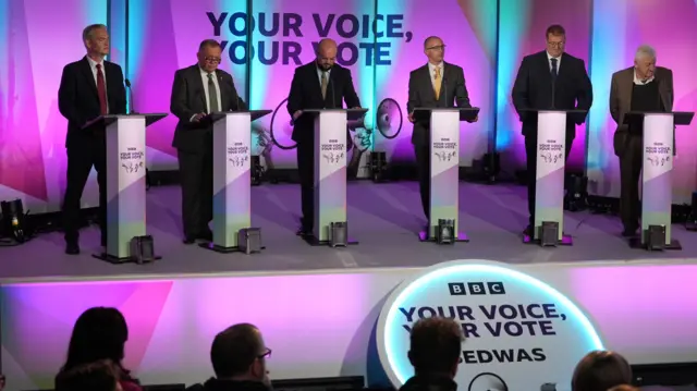 Debate candidates face the audience on stage
