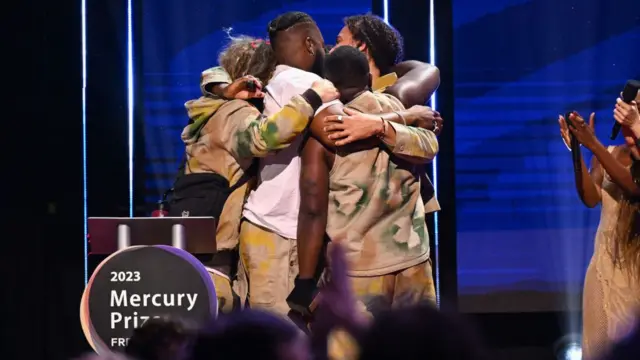 Mercury Prize winners Ezra Collective hugging on stage