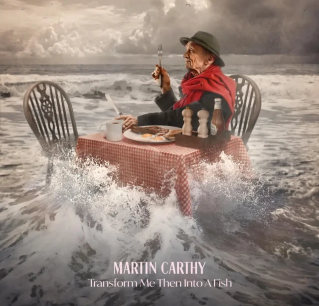 Carthy's album cover, showing him eating a fry up while sat on a table in shallow ocean waters